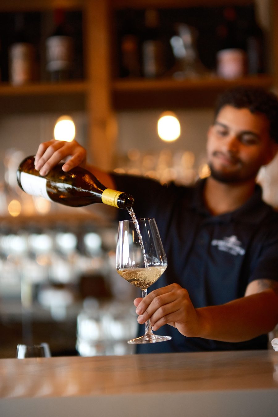 Apizza Brooklyn bartender pouring a glass of white wine